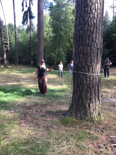 Frau mit Augenbinde beim "Seiltanzen" im Wald